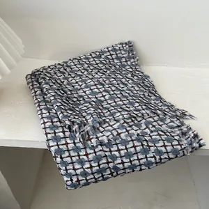 Detail of Korean plaid knit scarf featuring blue and brown fringe with soft texture