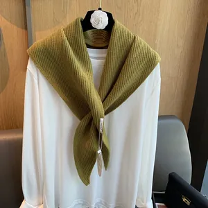 Makroansicht der olivgrünen Strickschal-Textur mit detailliertem gewebtem Markenetikett