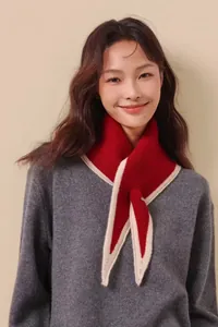 Close-up of red and white knit cross scarf showing soft texture on gray sweater