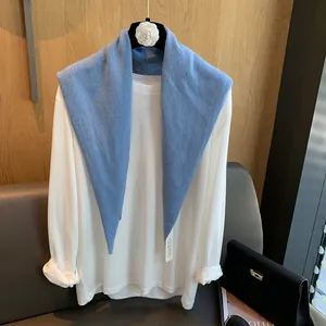 Detailansicht eines nebelblauen Strick-Wollschals über einem weißen Langarmshirt