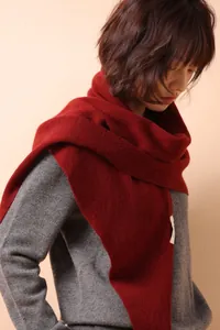 Detail of burgundy knit wool triangle scarf showing soft texture and premium quality label