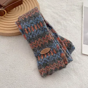 Detailopname van dikke gebreide Fair Isle sjaal met golfpatronen en lederen merklabel