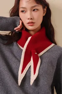 Close-up of red knit neck scarf with beige trim and decorative metal buckle detail
