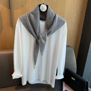 Detailansicht des grauen Wollstrick-Dreiecksschals über einem weißen Langarmshirt