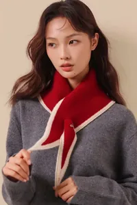 Detail of red and cream knitted triangular scarf with contrast trim and buckle closure