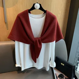 Detail showing white long-sleeve T-shirt with a dark red knitted shawl knotted at the front