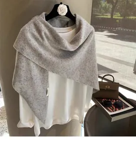 Detail shot of grey wool triangular scarf texture draped over white long sleeve shirt