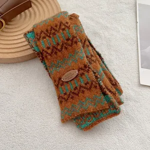 Detailopname van dikke Fair Isle gebreide sjaal met oranje en groene zigzagpatronen