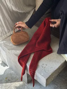 Détail d'un foulard triangle en laine crochetée rouge foncé et mini sac en daim marron