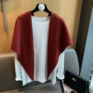 Detailed knit texture of brick red V-shaped triangular shawl on a wooden background