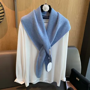 Detail eines blauen Strickschals über weißem Hemd auf floralem Kleiderbügel