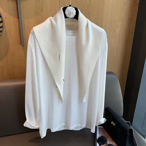 Detail of soft cream knit wool scarf styled over a white long-sleeve tee in minimalist style
