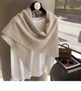 Detail of light beige wool knit shawl showing soft texture and speckled fiber pattern