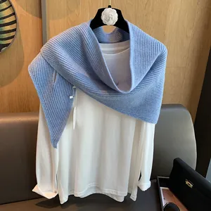 Detail eines himmelblauen Strickschals mit Rippenmuster auf weißem Oberteil