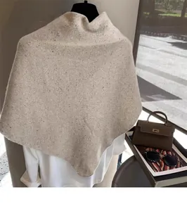 Detailed knit texture of beige wool blend poncho with speckled Donegal pattern detail