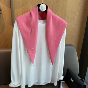 Detail of soft pink 100% wool knitted scarf with button styled with a white long-sleeve tee