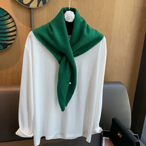 Detail view of emerald green 100% wool knitted scarf with silver button on white shirt