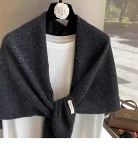 Detail of 100% wool label on dark grey knitted shawl draped on a boutique hanger