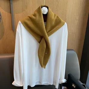 Close-up of ginger yellow wool knit scarf paired with a minimalist white cotton tee
