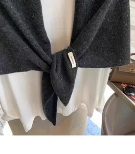 Macro shot of dark grey 100% wool knit shawl texture and stylish knotted draping style