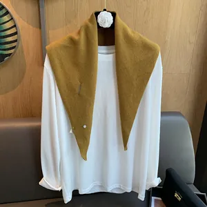 Detail showing ginger yellow knit shawl collar with button on white long sleeve shirt