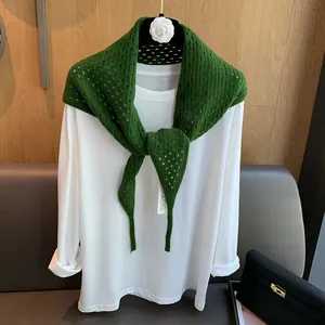 Détail d'une écharpe triangle en laine verte ajourée avec texture en maille et étiquette