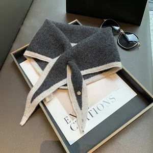 Detailed view of the dark grey knitted triangle scarf with ivory border and metal button