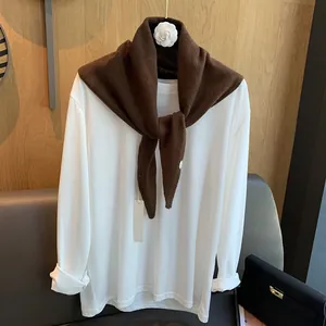 Detailstruktur des braunen 100% Wollstrickschals kombiniert mit einem weißen Baumwolloberteil