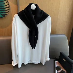 Detail of white long-sleeve cotton tee with black knit shawl and camellia brooch