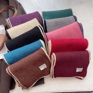 Détail d'écharpes en maille de laine multicolores avec bordure contrastée et étiquette