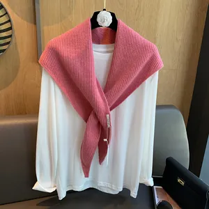 Details des rosa Strick-Dreieckstuchs mit Rippenstruktur und gewebtem Etikett auf T-Shirt