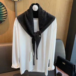 Detail eines weichen dunkelgrauen Wollstrickschals über einem minimalistischen weißen Oberteil