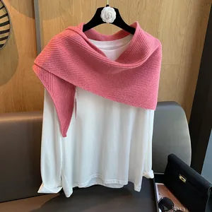 Detailansicht eines rosa gerippten Strickschals drapiert über einem weißen Langarmshirt