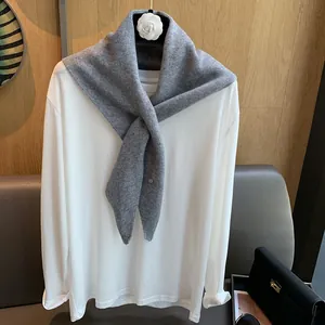 Detailed texture of gray wool knitted scarf paired with a white minimalist long-sleeve tee