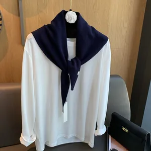Detail eines dunkelblauen Woll-Dreieckstuchs, drapiert über ein weißes Langarmshirt