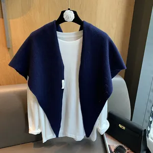 Detailed knit texture of dark blue shawl vest layered over a white casual long sleeve top
