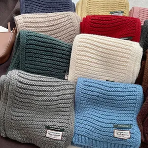 Close-up of thick rib-knit wool blend scarves with woven fabric labels in various colors