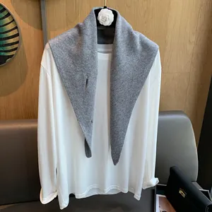 Detail of grey knitted wool scarf with white camellia flower brooch on white T-shirt