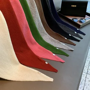 Nahaufnahme hochwertiger Woll-Dreieckstücher in vielen Farben mit kleinen Metall-Logo-Tags