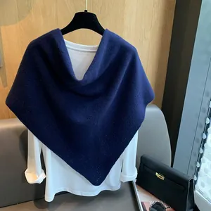 Detail shot of navy blue hollow knit triangular shawl draped over a simple white shirt