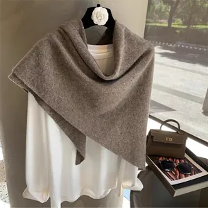 Brown 100% Australian wool knitted shawl scarf displayed on a hanger with lifestyle props