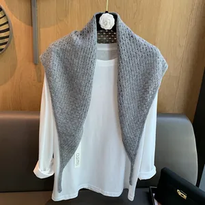 Détail d'un foulard triangle gris en laine ajourée présenté sur un haut blanc élégant