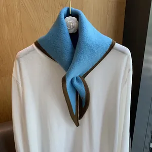 Close-up of sky blue knitted neckerchief with dark brown edges on white shirt