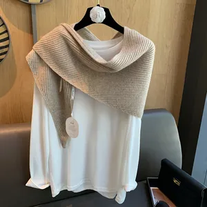 Detail eines beigen gerippten Strickschals über einem weißen Shirt für den Lagenlook