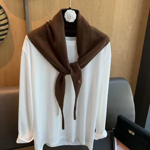 Detaillierte Strickstruktur der dunkelbraunen Wollschalmischung über weißem Langarmshirt