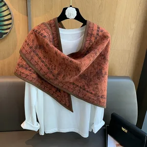 Vintage orange paisley triangle shawl scarf displayed on a grey leather sofa