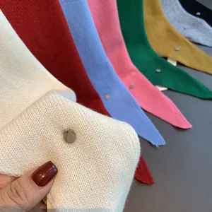 Macro shot of fine wool knit scarves with multiple colors and a round metal logo tag