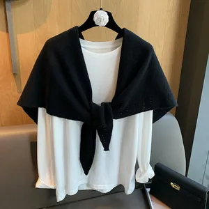Detail of the black hollow-out knitted triangle shawl styled over a white long-sleeve T-shirt