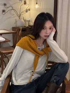 Détail d'un châle en laine ajouré jaune gingembre avec un cardigan en maille ivoire