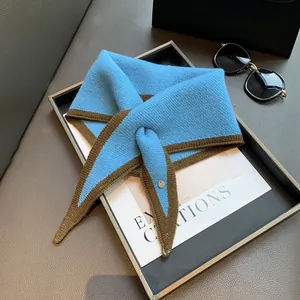 Detail of blue and brown color-block knit scarf styled with modern accessories